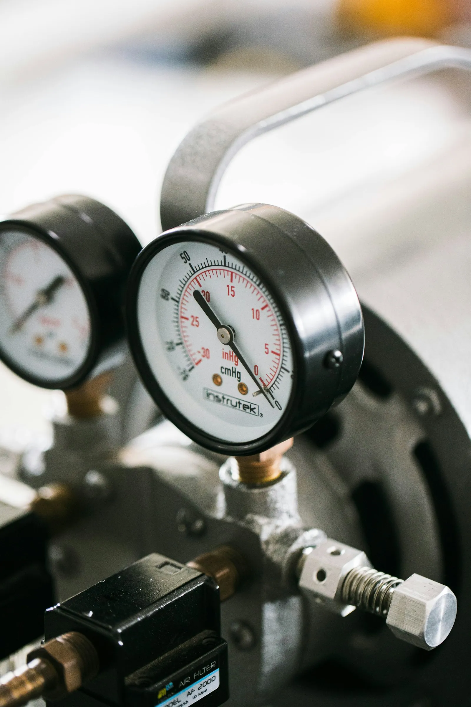 Teknisi menggunakan manifold gauge untuk mengukur tekanan freon AC