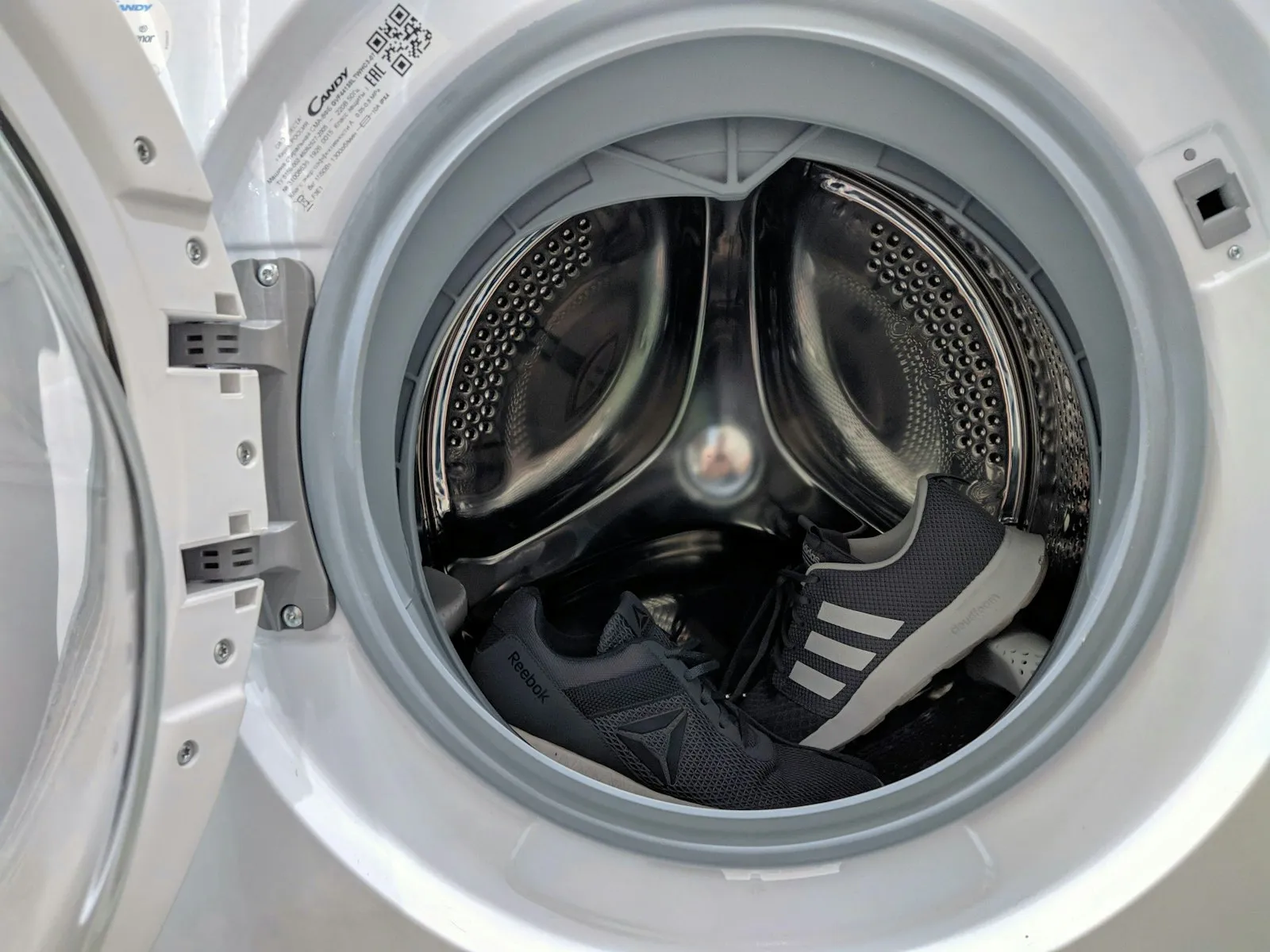 Teknisi membuka panel mesin cuci front loading untuk memeriksa komponen